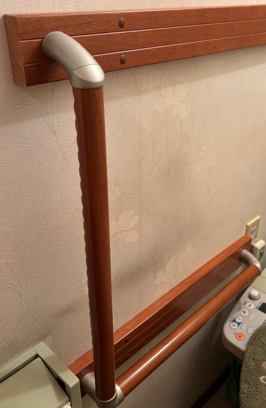 トイレのL字型の手すり。縦の棒の下から、壁に沿って横の棒がつながっている